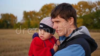 年轻的父亲手牵着孩子看日落。 温柔和怀抱的挚爱父亲.. 室外